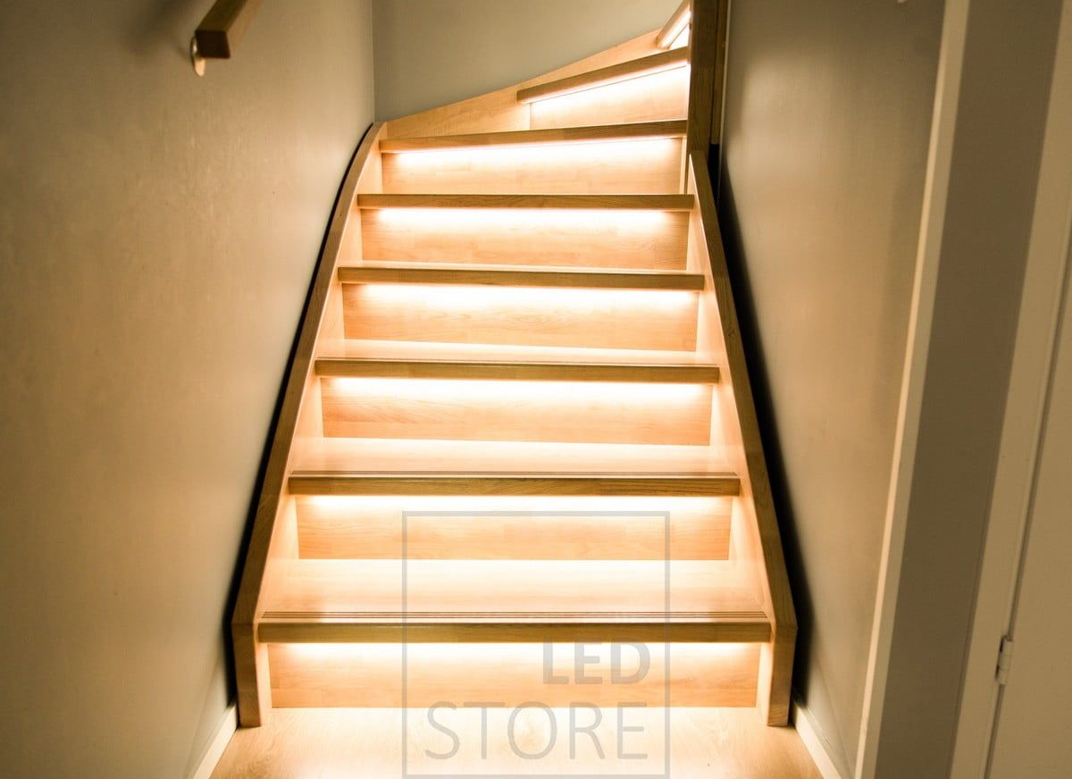 Wooden staircase illuminated by led strips on the steps, mounted on the staircase lip